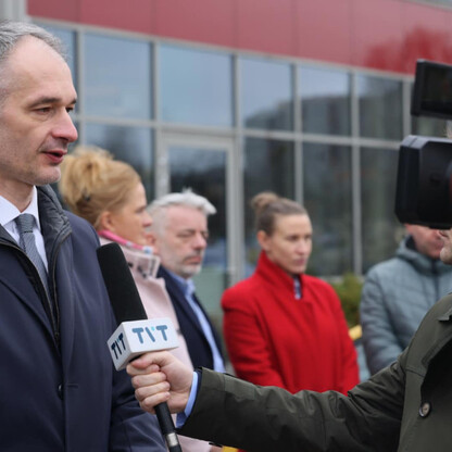 Mężczyzna w rozmowie z dziennikarzem przed modernnym budynkiem. Projekt Tyskiego HUB dla zielonej gospodarki. (wygenerowano przez AI)