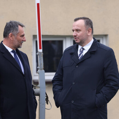 Dwa mężczyźni w garniturach omawiają przebudowę skrzyżowania w Bieruniu, na tle budowy i barier. (wygenerowano przez AI)