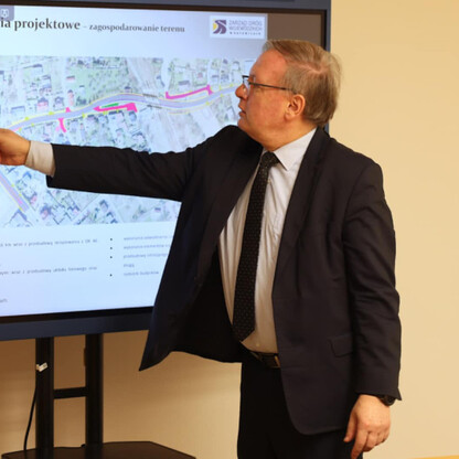 Mężczyzna w garniturze prezentuje plan inwestycji drogowej na ekranie, wskazując na mapę w Bieruniu, Polska. (wygenerowano przez AI)